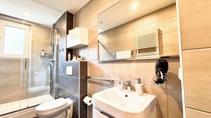 Une salle de bain moderne avec une douche à parois de verre, des toilettes, un lavabo et un porte-serviettes.