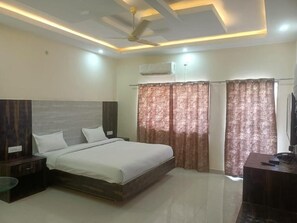 A bedroom with a bed, nightstands, a desk, and a ceiling fan.
