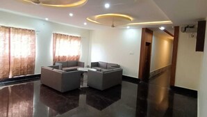 A spacious living area with a glossy black floor, a sectional sofa, and a ceiling with recessed lighting. - Hotel Rajwada Palace (Nivari)