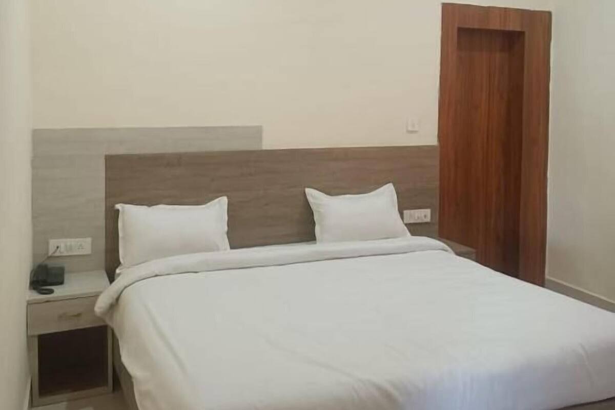 Quarto com cama, mesa de cabeceira e porta de madeira.