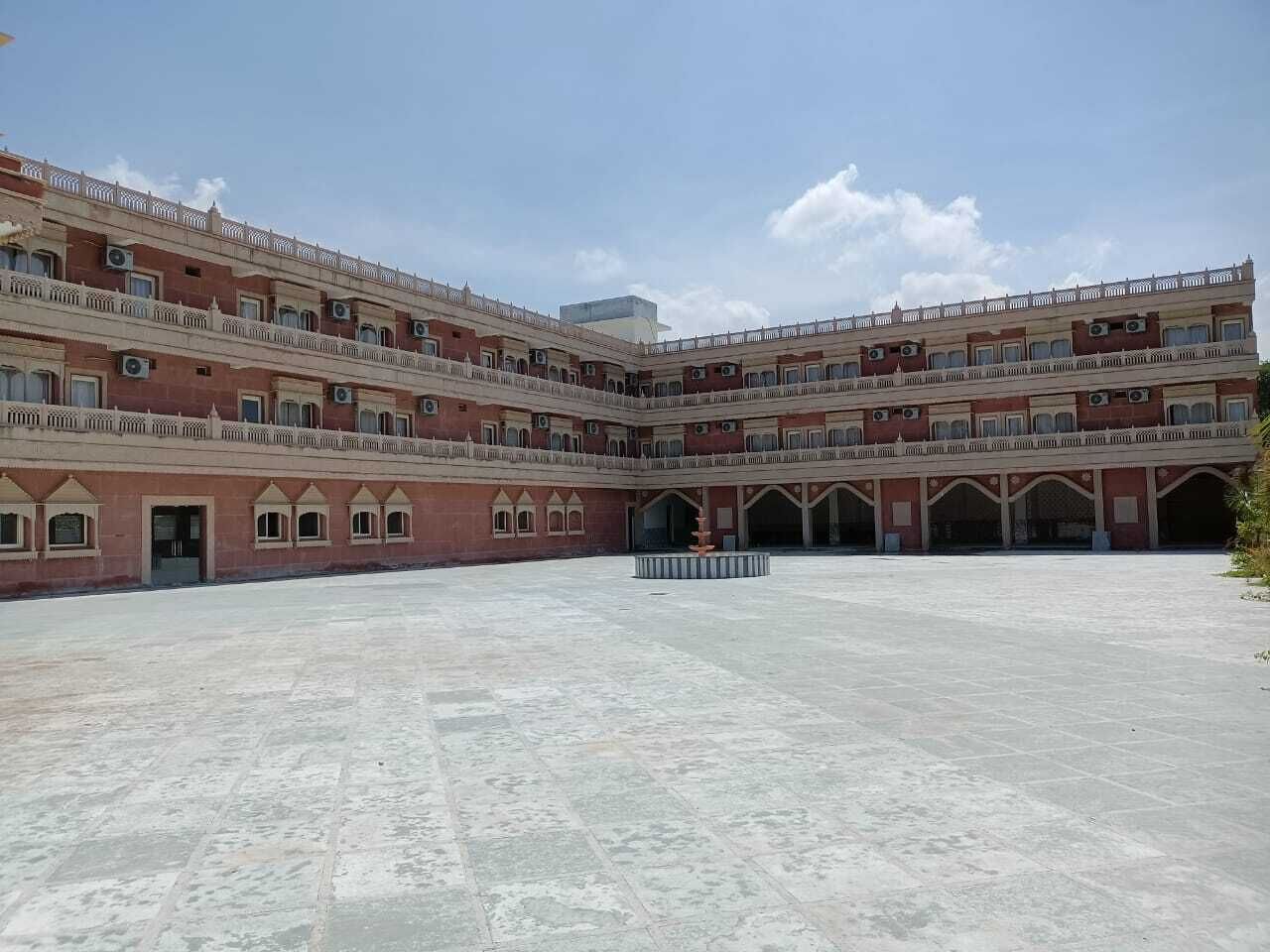 A large courtyard with a multi-story building featuring arched windows and balconies.