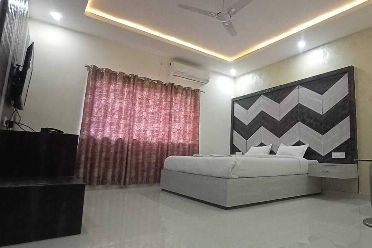 Quarto moderno com cama, televisão grande montada na parede, ventilador de teto e uma peça decorativa na parede.