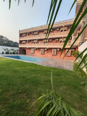 Un edificio de varios pisos con una piscina en primer plano.