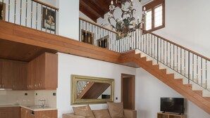 Un vaste espace de vie comprenant un escalier en bois, un canapé, une table basse et un téléviseur.