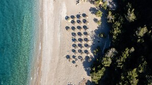 Vue aérienne d’une plage où l’on aperçoit un agencement circulaire d’objets, possiblement des tentes, près du bord de l’eau.