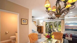A living room with a glass coffee table, wicker chairs, a sofa, and a TV. - Doc`s Paradise (Key West)