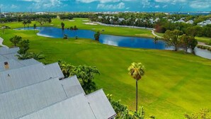 A golf course with multiple ponds, a clear blue sky, and residential buildings in the background. - Doc`s Paradise (Key West)