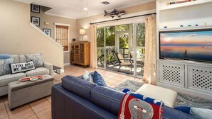 A living room with a sofa, a television, and a ceiling fan. - Doc`s Paradise (Key West)