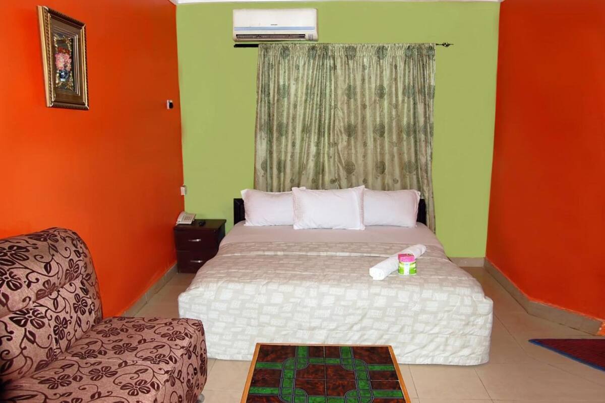 A room with a bed, a nightstand, a chair, and a patterned rug.