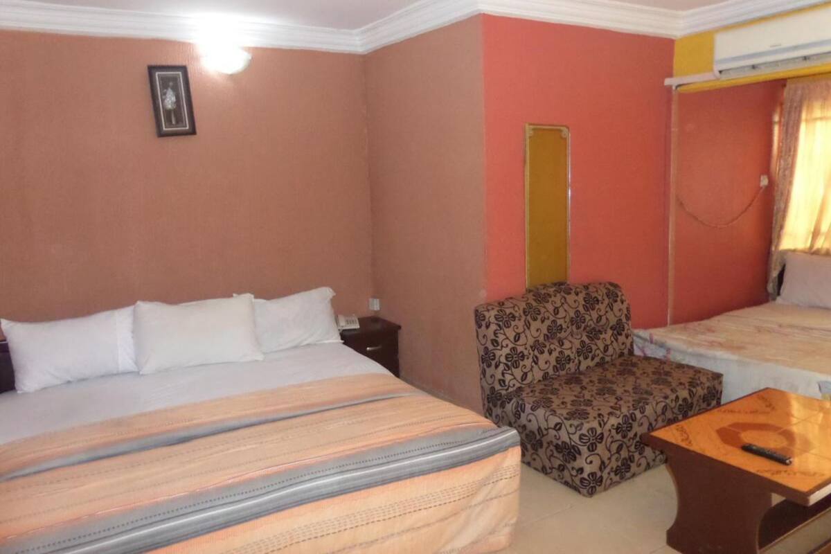 A hotel room with a bed, a chair, a small table, and a bunk bed.