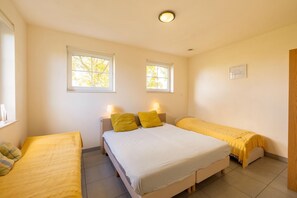 A bedroom with two beds, a window, and a bedside table with a lamp. - Holiday home in Sint Kruis with a garden (Sint Kruis)