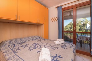 A bedroom with a bed, a window with a view, and a balcony with a table and chairs. - Casa Emozione With Shared Pool (Olbia)