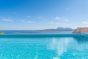 A clear blue pool with a view of the sea and distant mountains. - Casa Emozione With Shared Pool (Olbia)