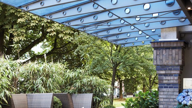 An outdoor seating area with wicker furniture and a blue ceiling with circular patterns. - Boston Apartments HH (Hamburg)