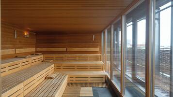 Una sauna moderna con bancos de madera y grandes ventanales con vistas a la ciudad.