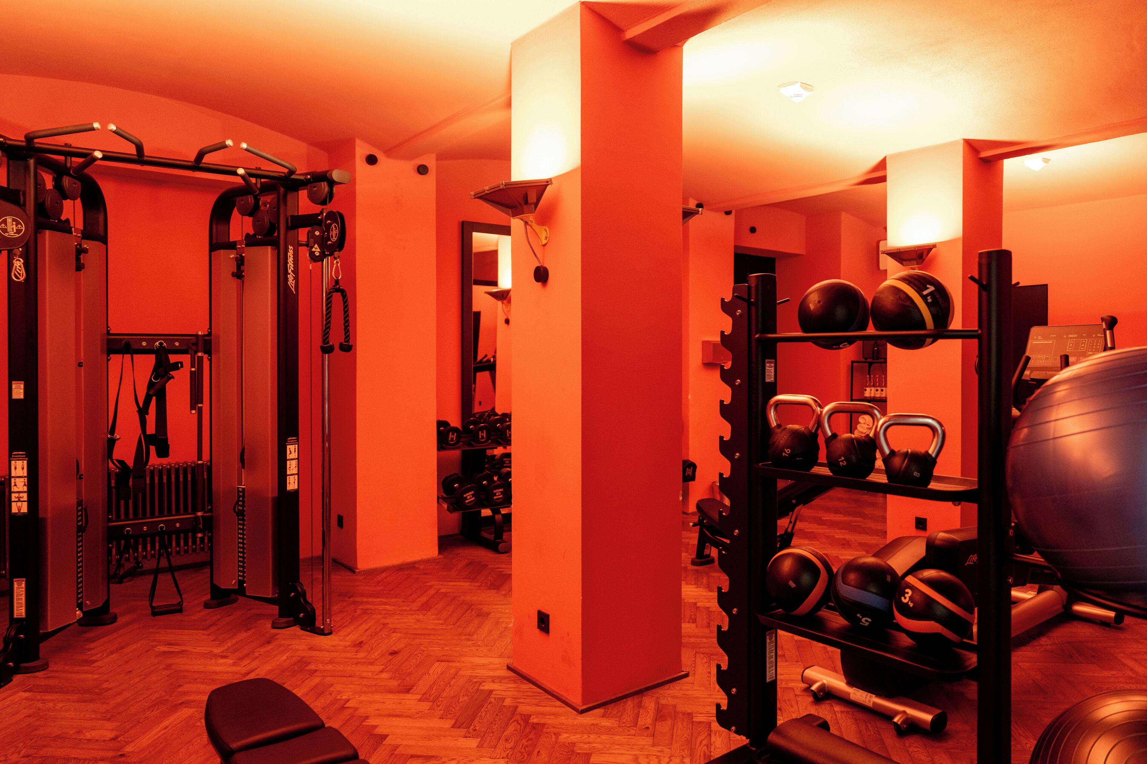 Ginásio com equipamentos de exercício, um banco e um suporte para kettlebells.