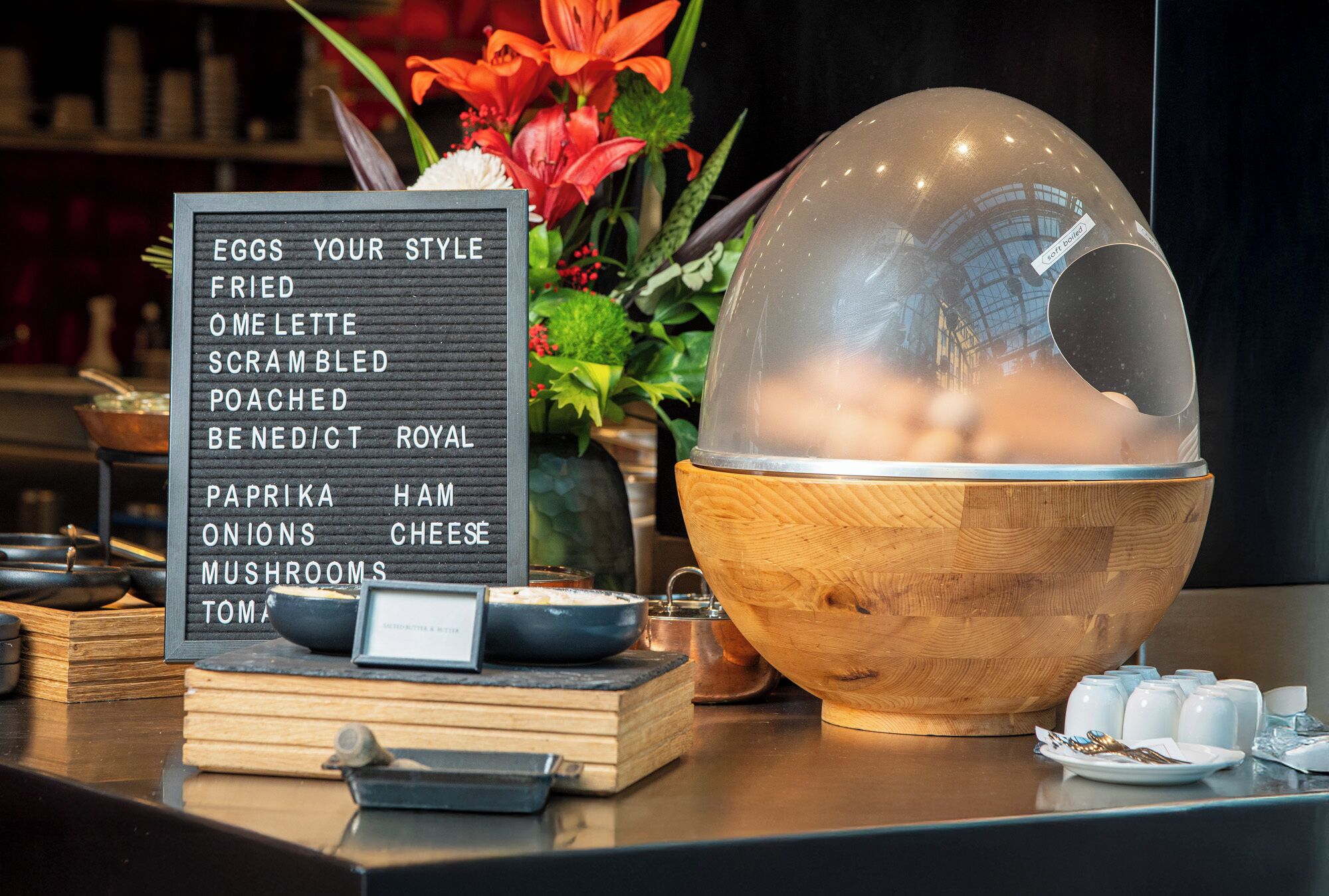 A menu board with various breakfast options, a wooden bowl, and a decorative glass sphere on a counter.