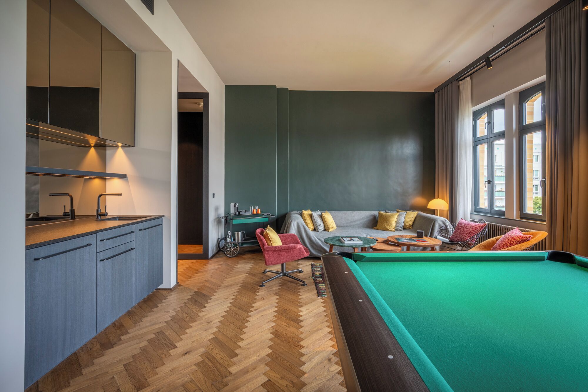 Ein modernes Wohnzimmer mit Billardtisch, einer Sofagarnitur und einer Bar.