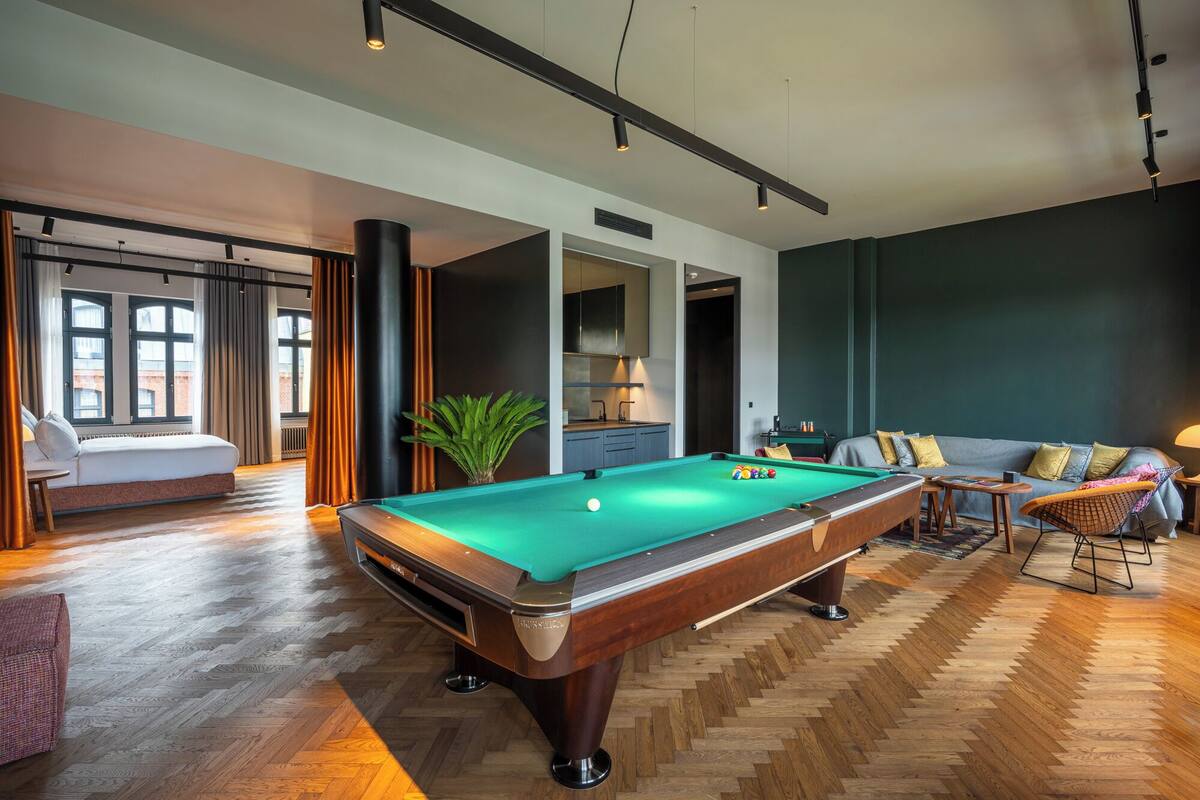 A modern living room with a pool table, a sofa, and a dining area.