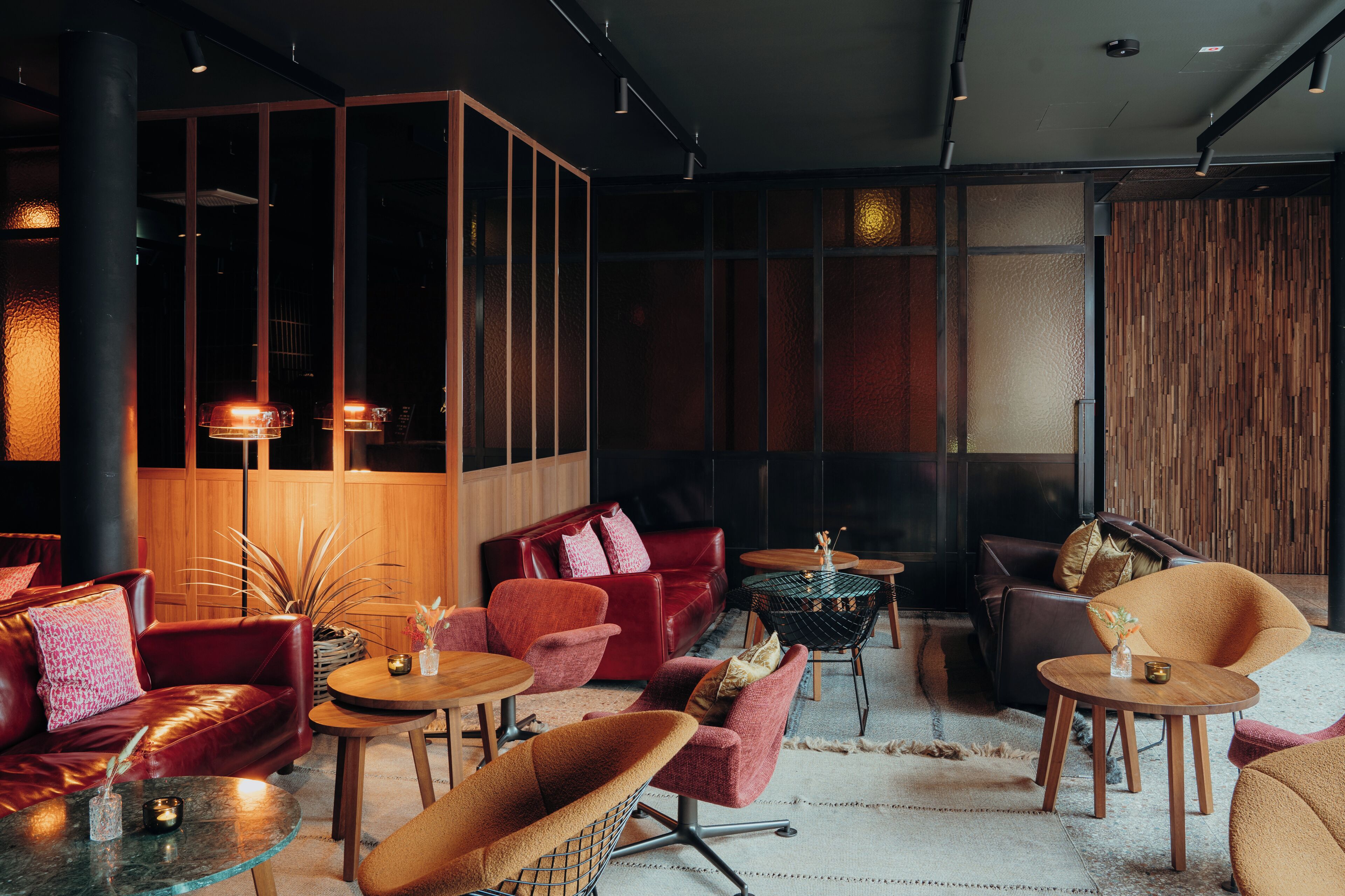A modern lounge area with leather sofas, round tables, and a mix of red and brown chairs.