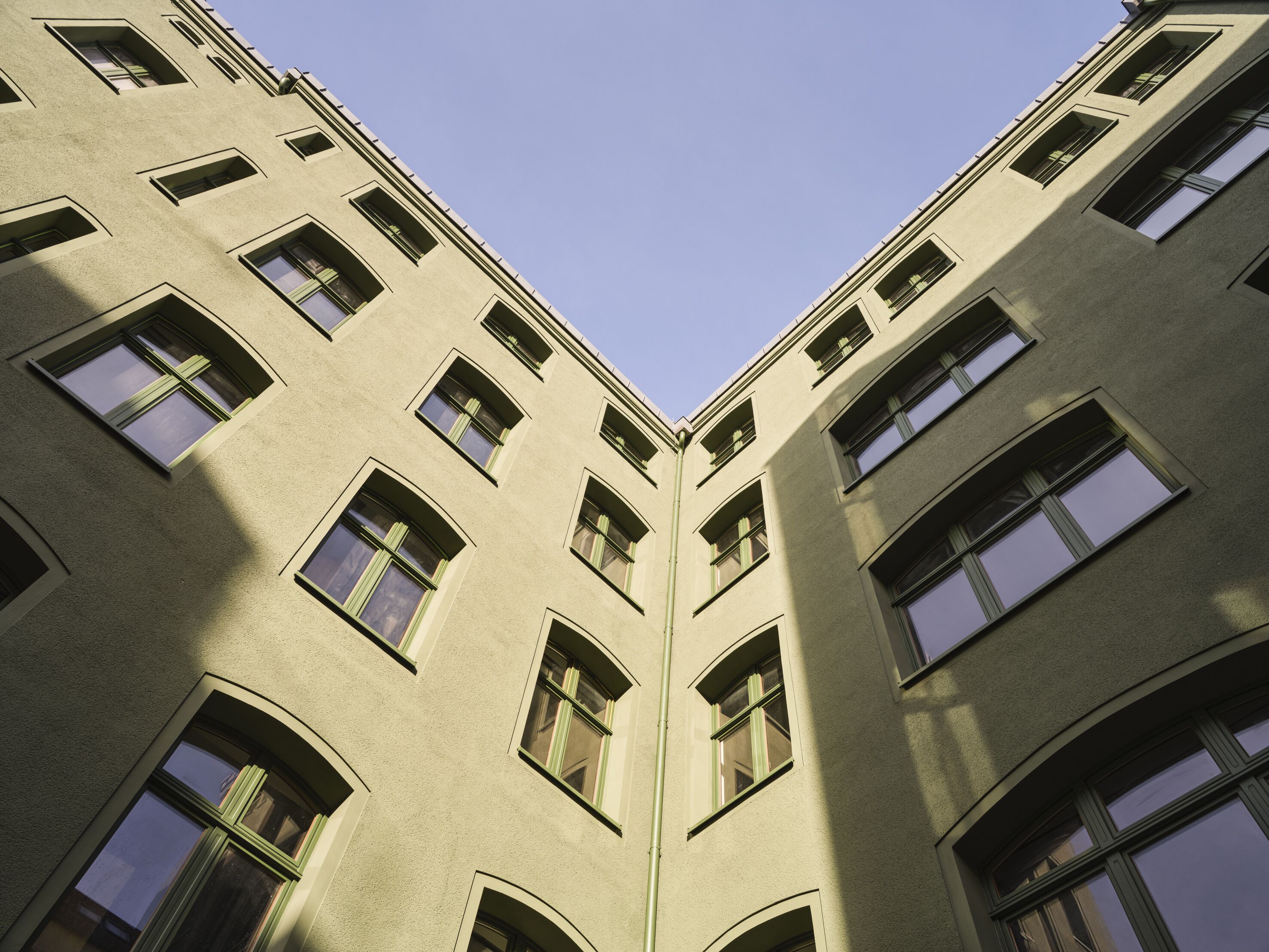 A corner view of a building with multiple windows and a textured facade.