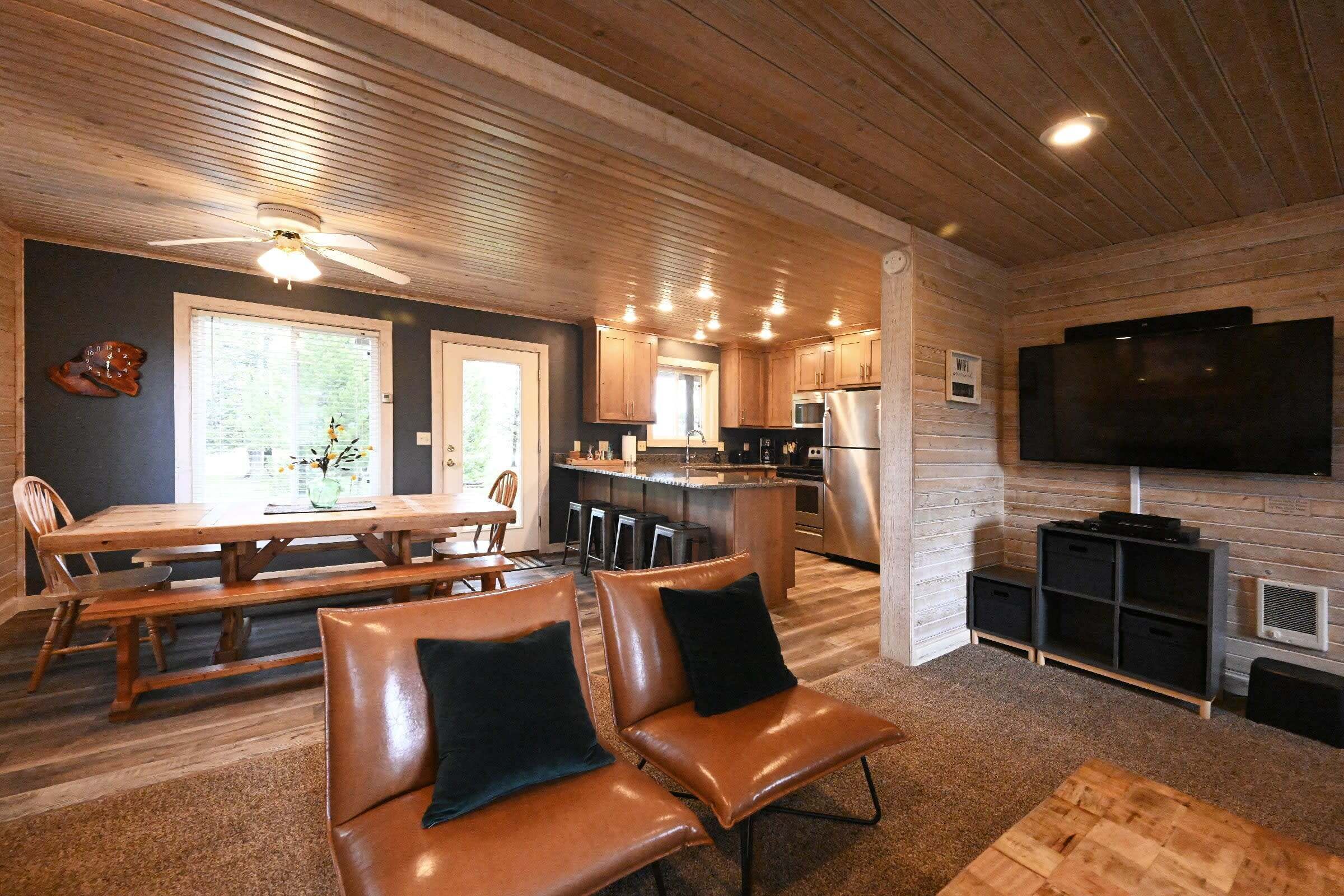 Una cocina moderna con una isla central, techo de madera y un televisor de pantalla plana en la pared.