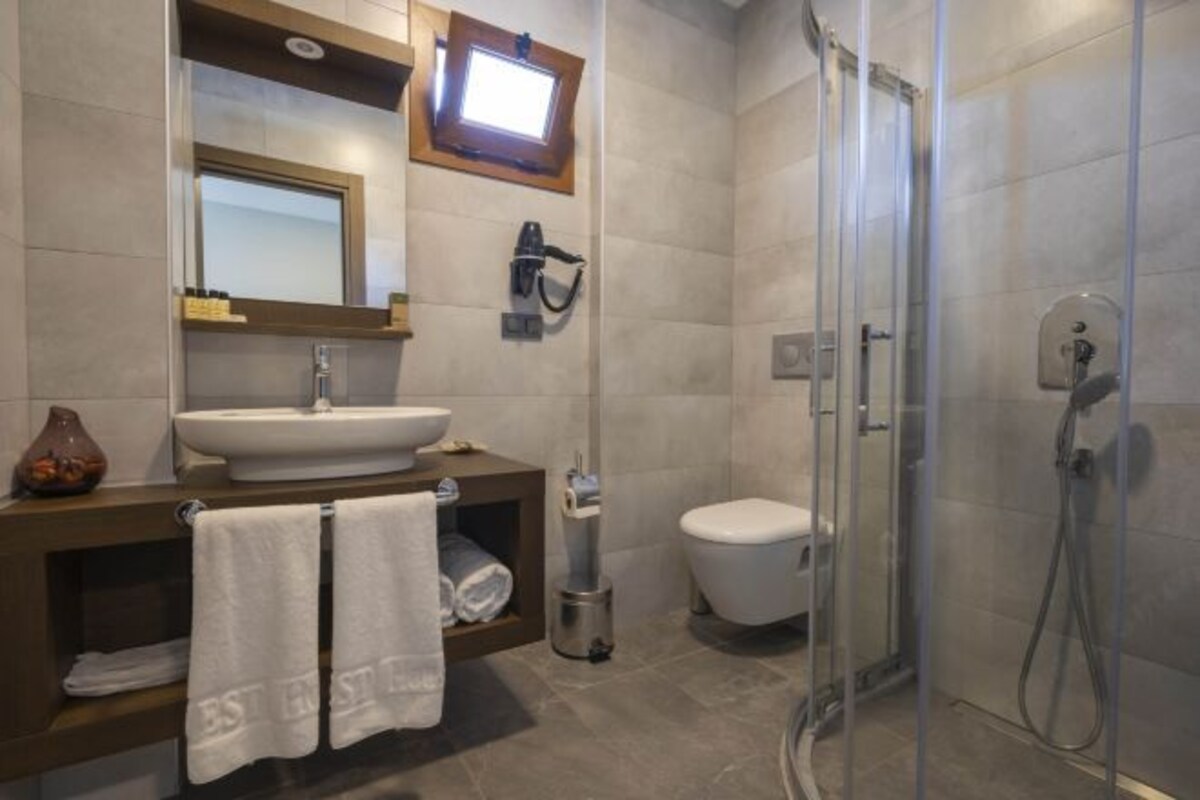 A modern bathroom with a sink, mirror, towel rack, toilet, and shower.