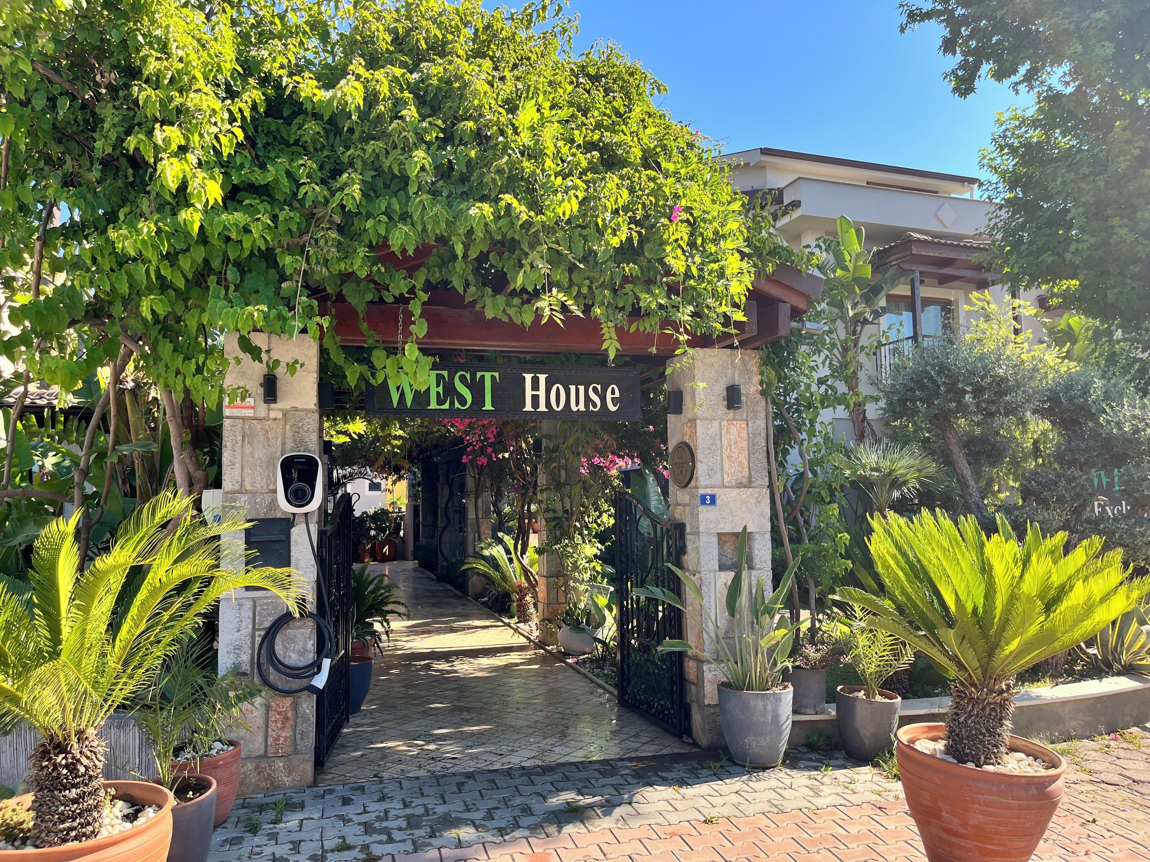 A pathway leading to a building with a sign reading 'WEST House'.