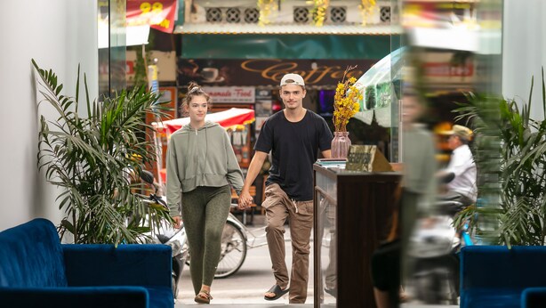 A couple walking through a public space with potted plants and a coffee shop in the background. - Sonata Central Hotel & Spa (Hanoi)