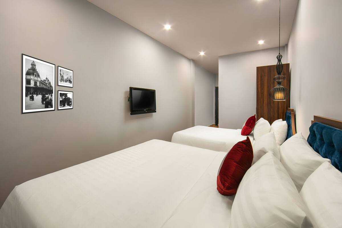 Une chambre d’hôtel moderne avec deux lits, un téléviseur à écran plat et trois photographies encadrées accrochées au mur.