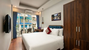 A hotel room with a large bed, wooden wardrobe, and a balcony with a view. - Sonata Central Hotel & Spa (Hanoi)