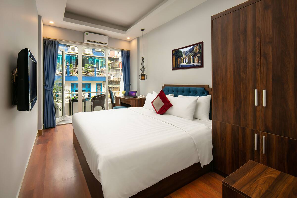 Une chambre d’hôtel avec un grand lit, une armoire en bois et un balcon avec vue.