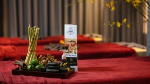 A spa setup with a tray of natural ingredients, a brochure, and a red towel on a bed. - Sonata Central Hotel & Spa (Hanoi)