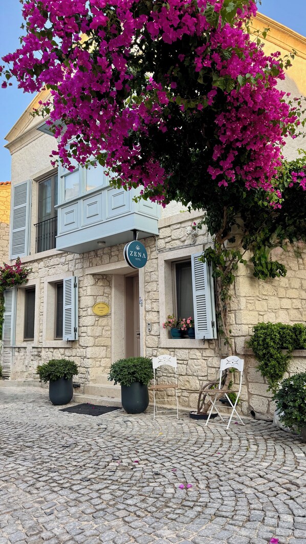 A stone building with a sign for Zena Hotel, a cobblestone street, and potted plants. - Zena Hotel Alaçatı Adults Only (Cesme)