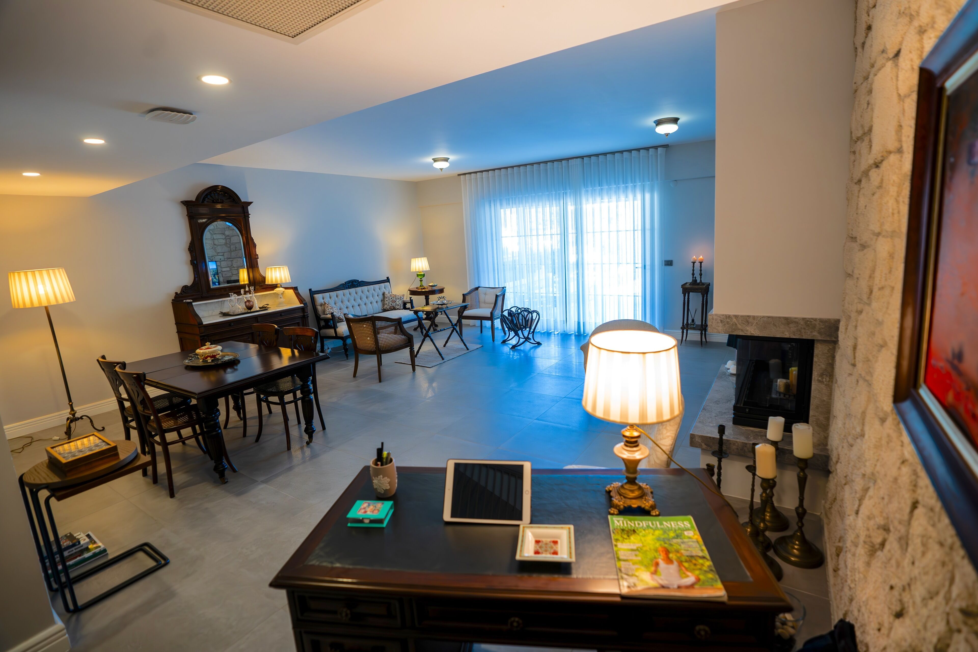 A spacious living room with a fireplace, a dining area, and a seating area with a large window.
