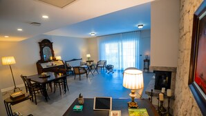 A spacious living room with a fireplace, a dining area, and a seating area with a large window. - Zena Hotel Alaçatı Adults Only (Cesme)