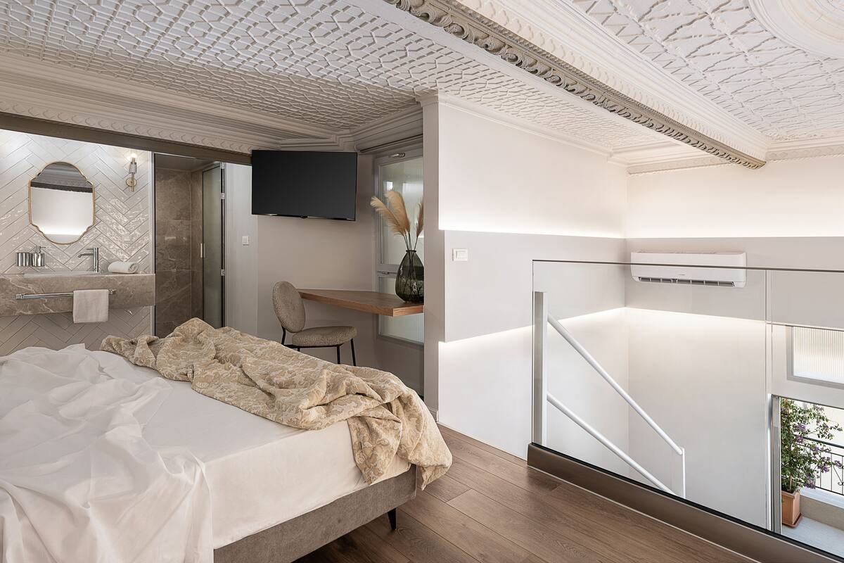 Une chambre moderne avec un grand lit, une coiffeuse avec un miroir, un téléviseur à écran plat et un bureau avec une chaise.
