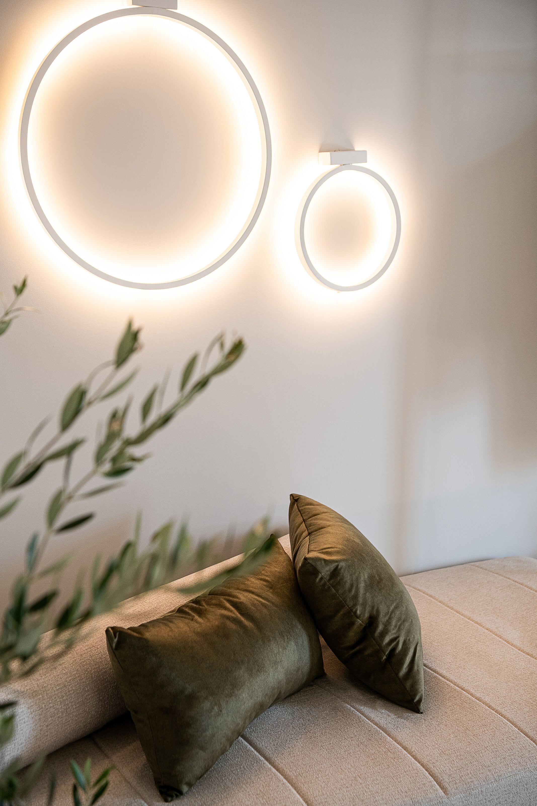 Una sala de estar moderna con un sofá, dos cojines y dos lámparas circulares fijadas a la pared.