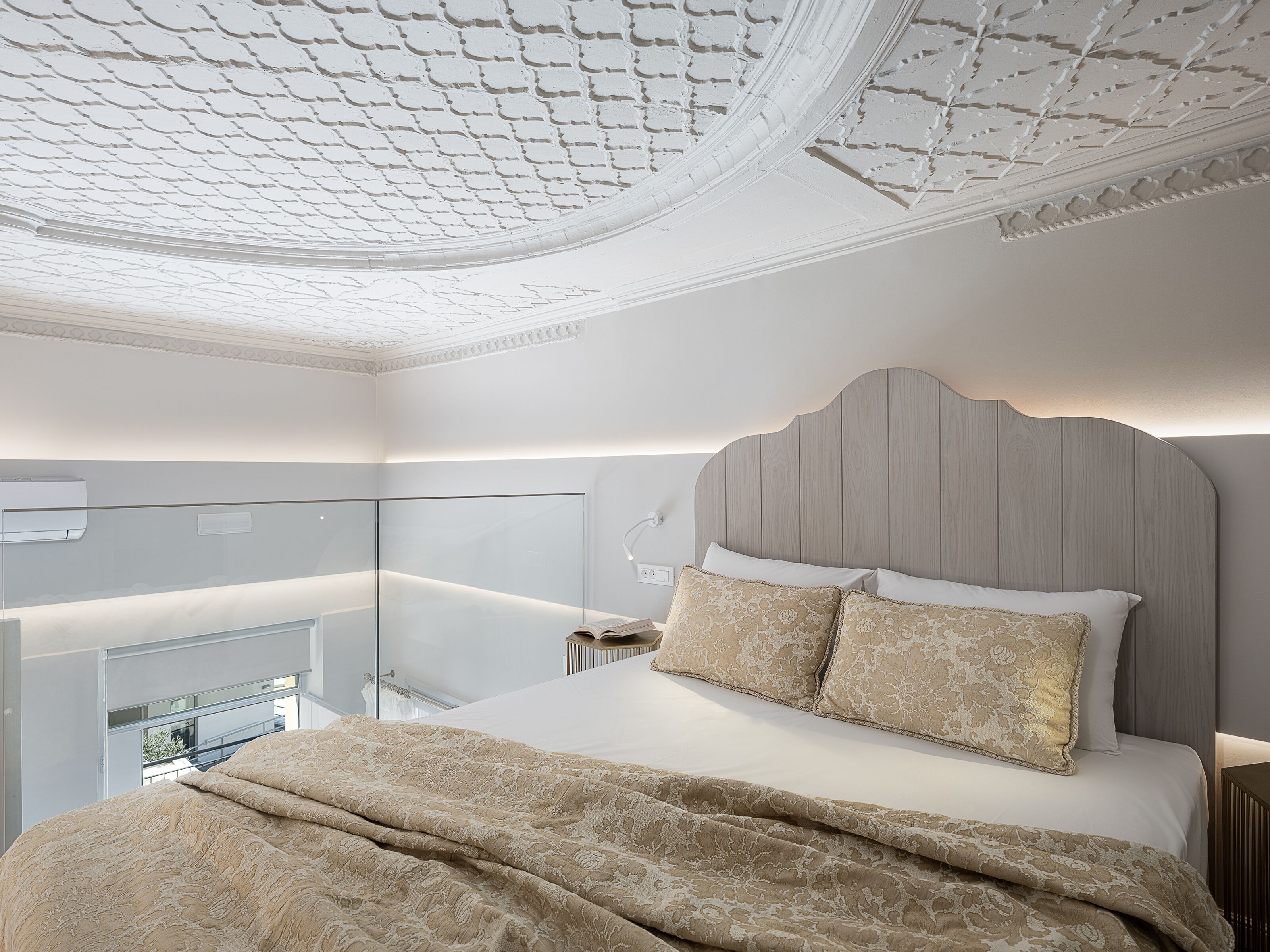 Un dormitorio con cama, mesita de noche, lámpara y un separador de vidrio.