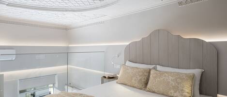 Un dormitorio con cama, mesita de noche, lámpara y un separador de vidrio.