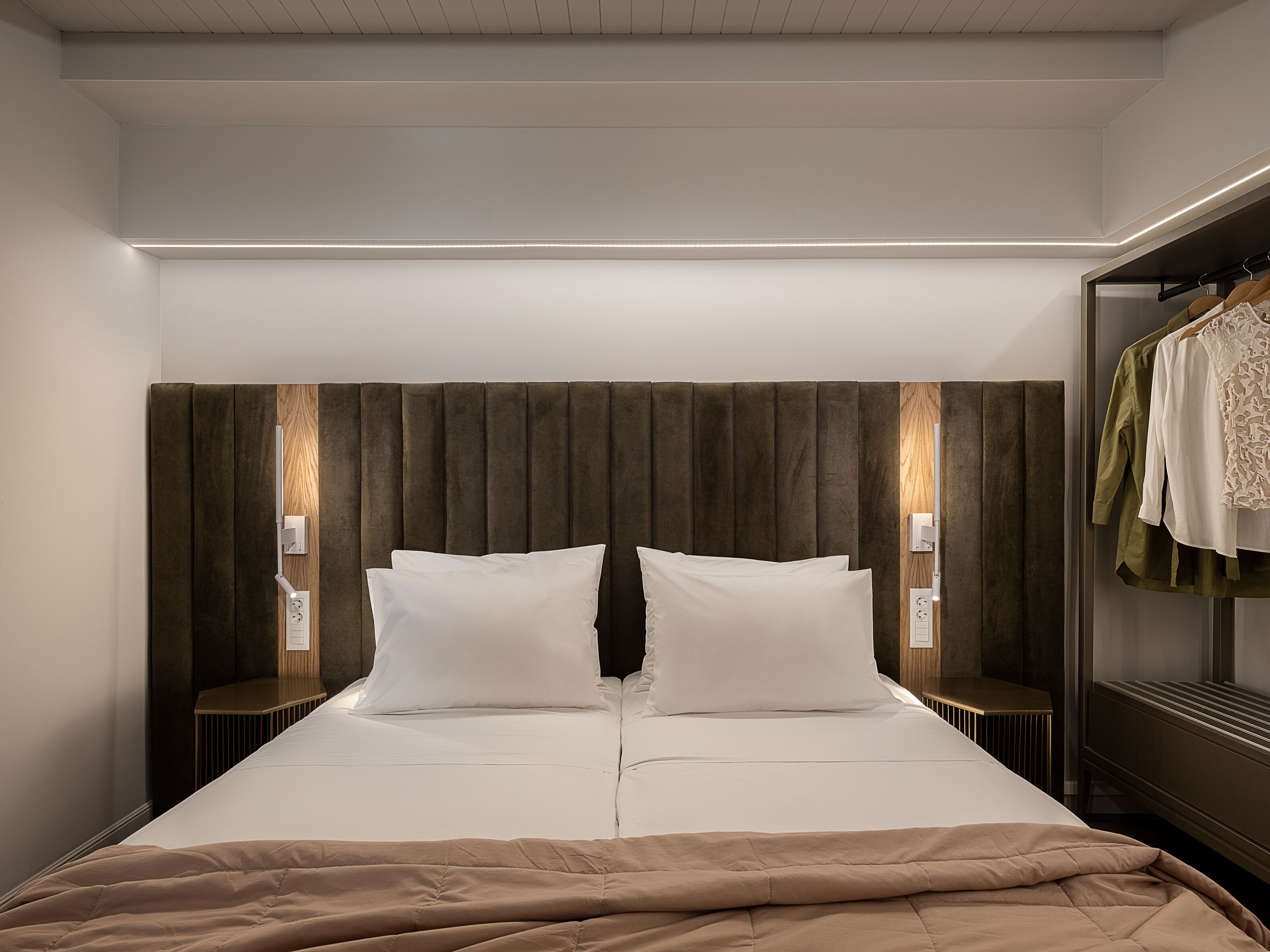 A modern hotel room with a large bed, a wardrobe, and two bedside lamps.