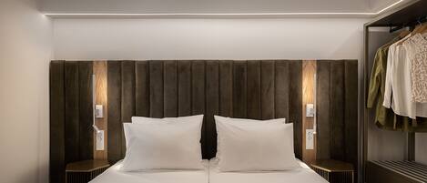 A modern hotel room with a large bed, a wardrobe, and two bedside lamps.