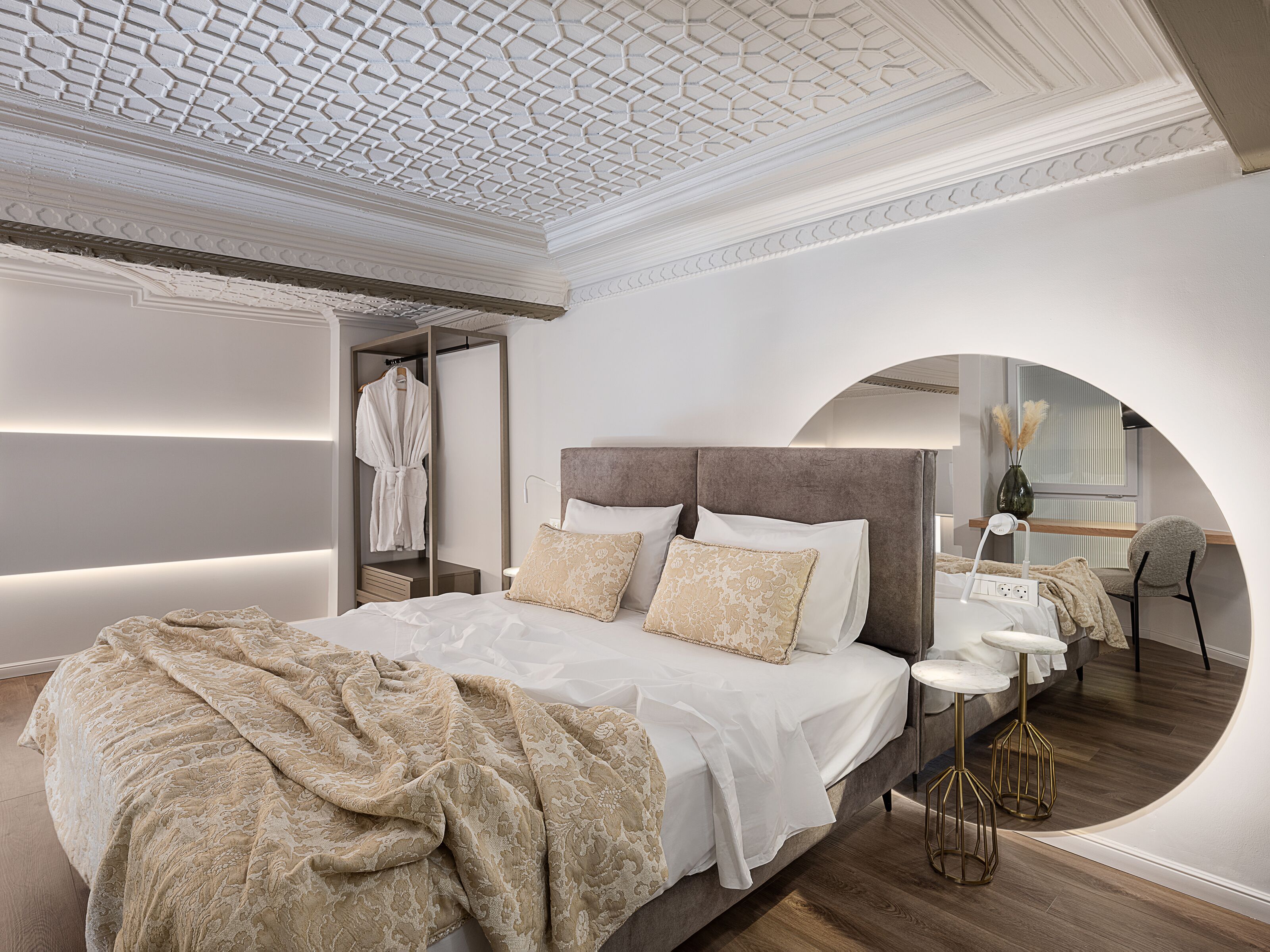 Un dormitorio moderno con una cama grande, un vestidor y una zona de estar con un escritorio y una silla.