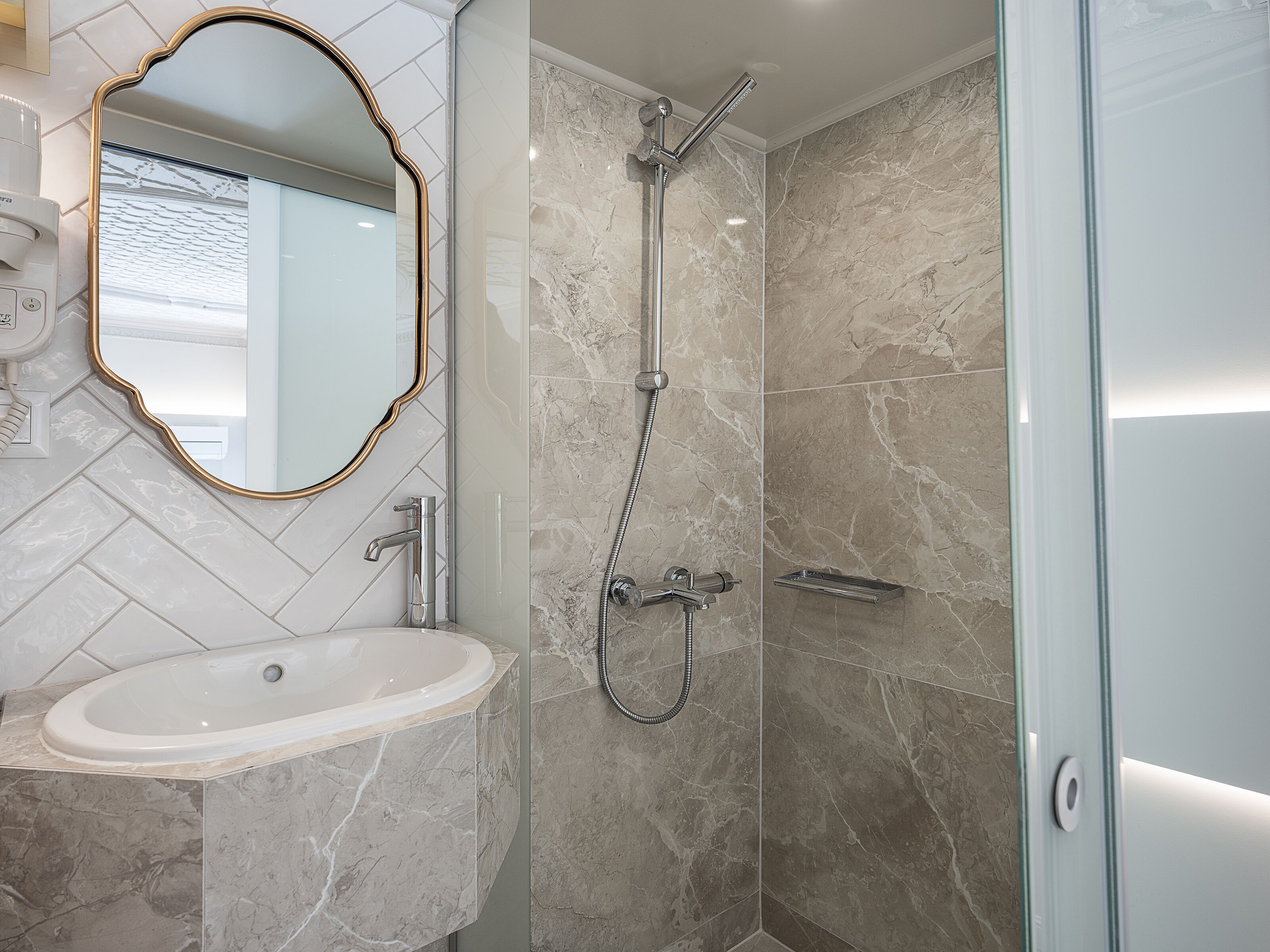 Un baño moderno con lavamanos, espejo y ducha.