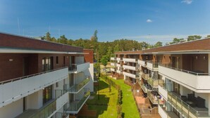 Un hotel moderno con varios balcones, un patio central y vistas al bosque circundante.