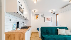 Una cocina compacta con armarios blancos, una encimera de madera y un sofá azul turquesa en la zona de estar.