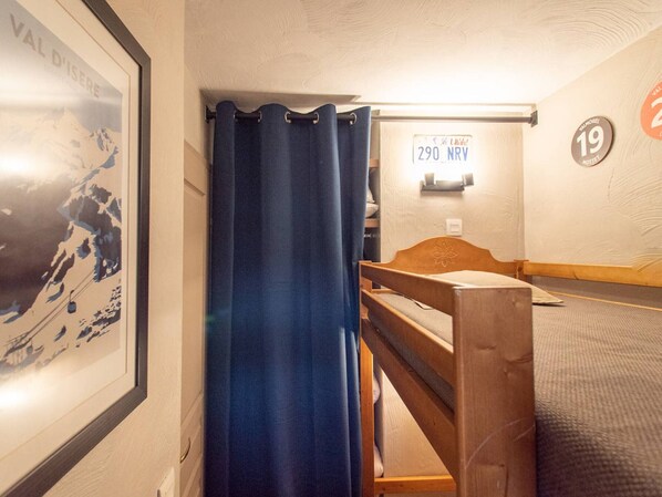 A hotel room with a bunk bed, a shower curtain, a framed picture, and a sign with a license plate.
