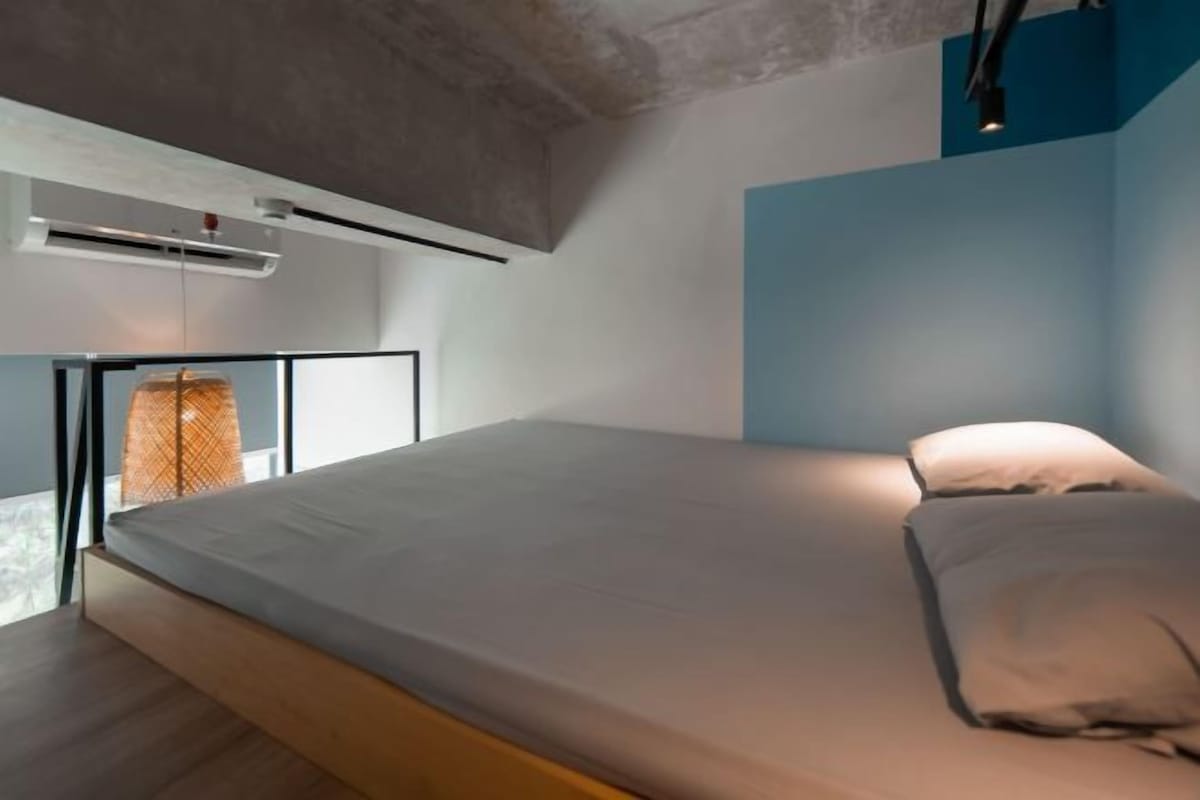 Ein modernes Schlafzimmer mit einem Bett, einer Pendelleuchte und einer Klimaanlage.