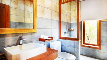 Een moderne badkamer met een houten wastafel, een grote spiegel, een douche en een raam met uitzicht op bomen.
