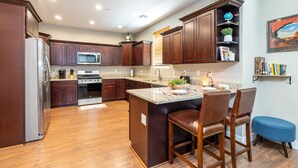 A modern kitchen with wooden cabinets, stainless steel appliances, and a central island with bar stools. - Luxurious AC Home Near Heart of Downtown, NAU, Snowbowl, Historic Route 66 (Flagstaff)